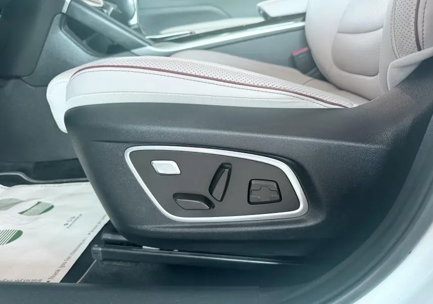 Gros plan sur les commandes électriques du siège avant droit en cuir beige et noir du Renault Koleos blanc 2021.