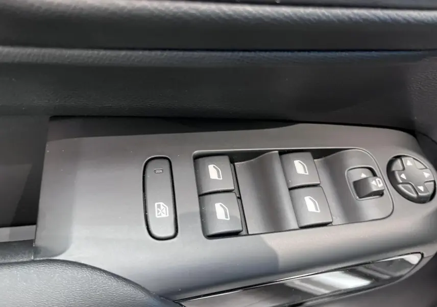 Gros plan sur les commandes de lève-vitres et réglages des rétroviseurs côté conducteur d'une Citroën C5 Aircross gris platinium.