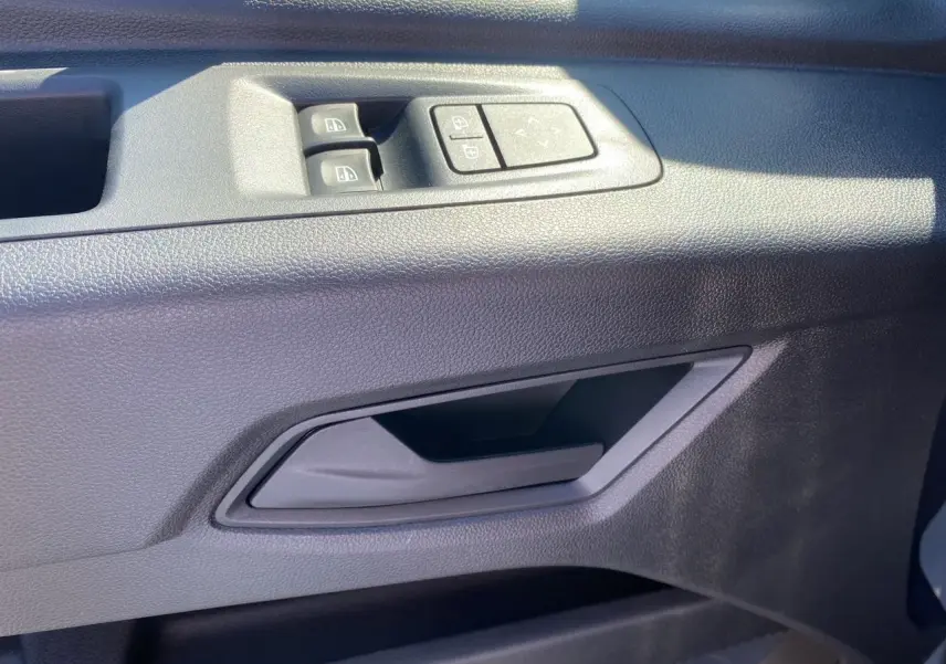 Poignée intérieure côté gauche de la porte avant du Renault Master gris urbain, avec commandes des vitres et rétroviseurs.
