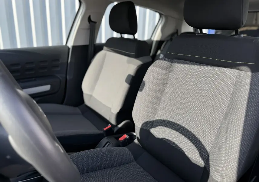 Intérieur de la Citroën C3 2023, vue sur les sièges avant en tissu gris clair et noir avec appuie-têtes.