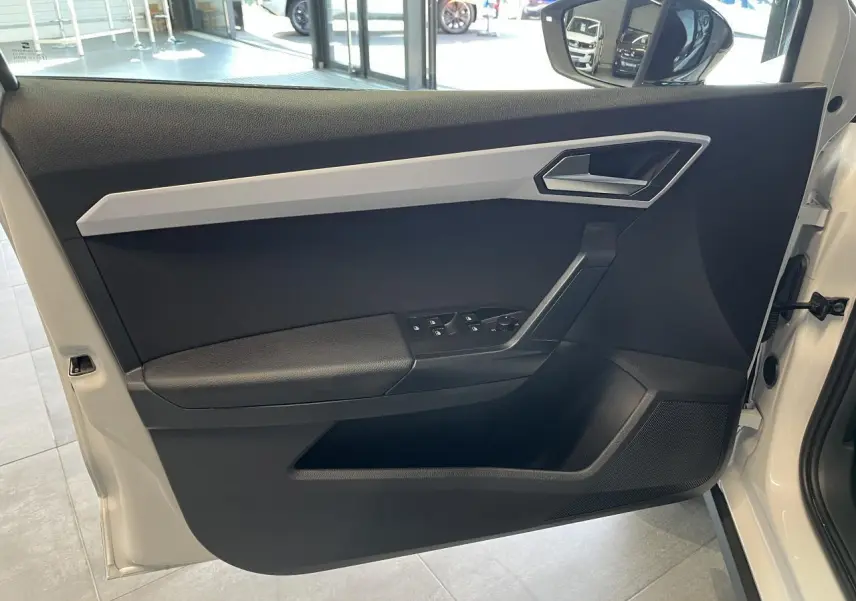Détail de la porte avant gauche blanche du SEAT Arona 2024 avec commandes de vitres et rétroviseur.