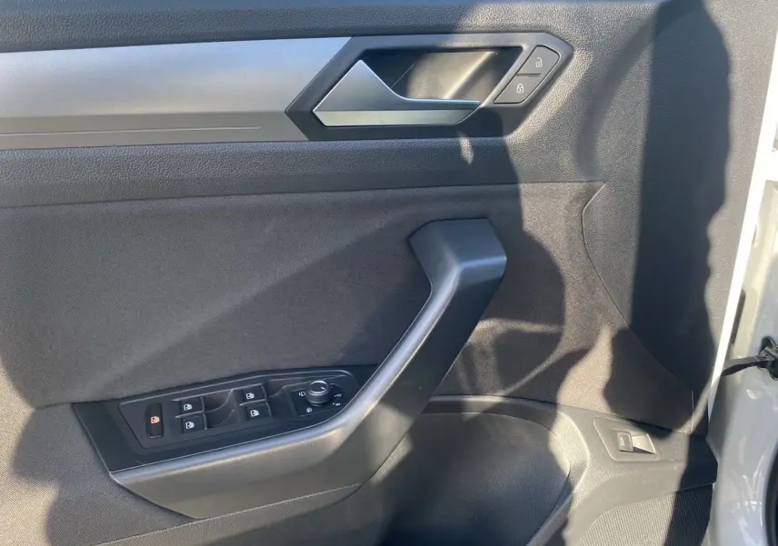Vue rapprochée de la porte avant gauche intérieure du Volkswagen T-Roc Silver White avec commandes de vitres et serrure.
