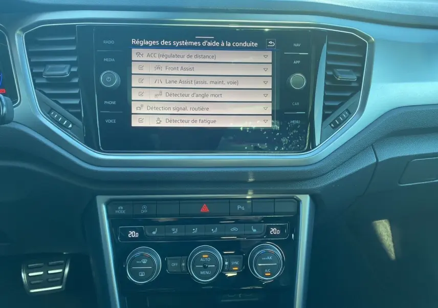 Vue rapprochée de l’écran tactile et de la console centrale du Volkswagen T-Roc 2021 avec affichage des aides à la conduite.