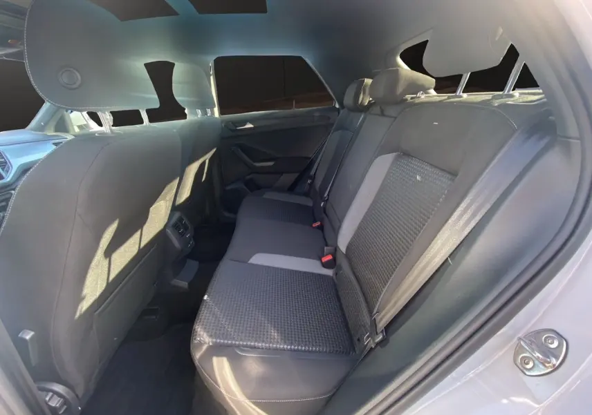 Vue intérieure arrière droite du Volkswagen T-Roc 2021 avec sièges tissu noir et toit ouvrant panoramique visible.
