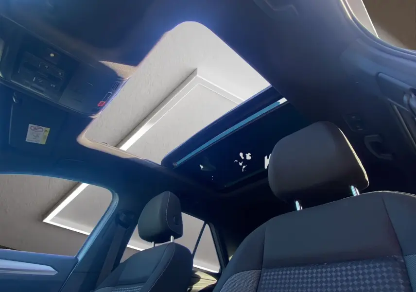 Intérieur du Volkswagen T-Roc 2021 avec toit ouvrant panoramique, sièges noirs et vue vers l'avant côté conducteur.