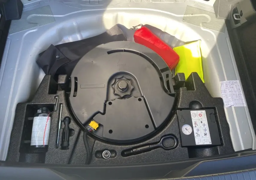 Coffre ouvert du Volkswagen T-Roc 2021 silver white montrant la roue de secours et les outils de bord.