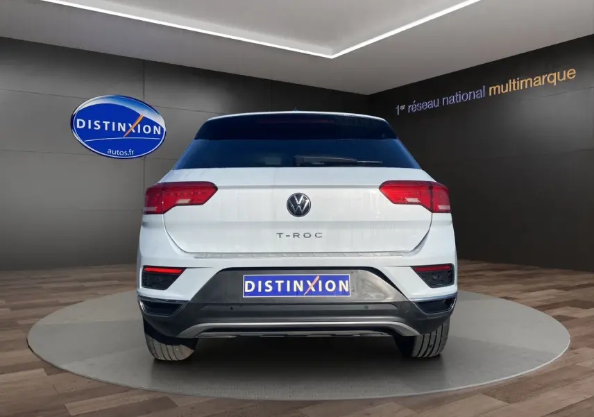 Vue arrière d'un Volkswagen T-Roc blanc argenté 2021 avec hayon motorisé et logo Distinxion visible.