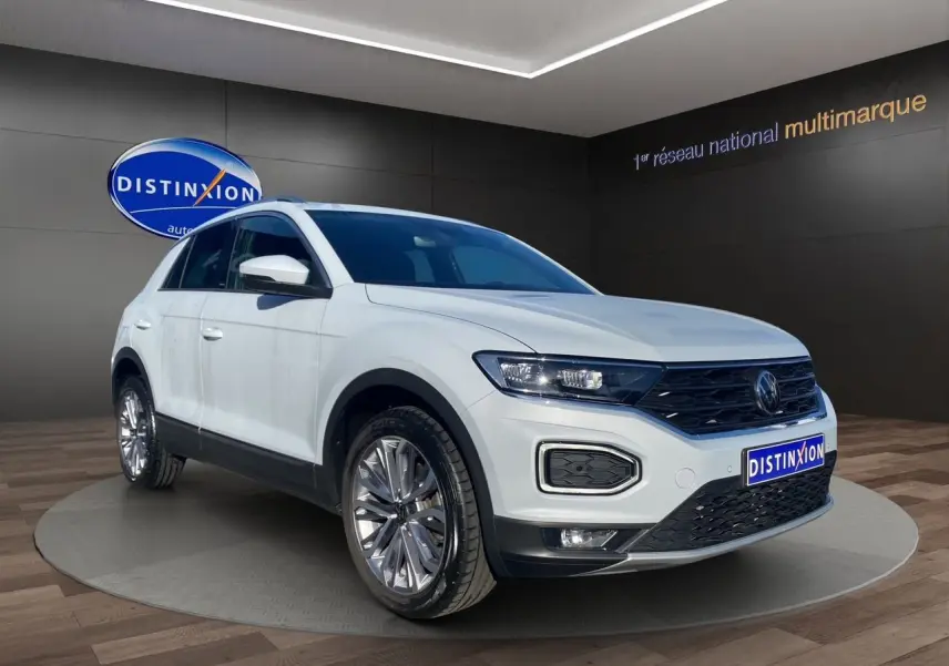 Volkswagen T-Roc Silver White en 3/4 avant droit, avec jantes alu 18 pouces et toit ouvrant panoramique visible.