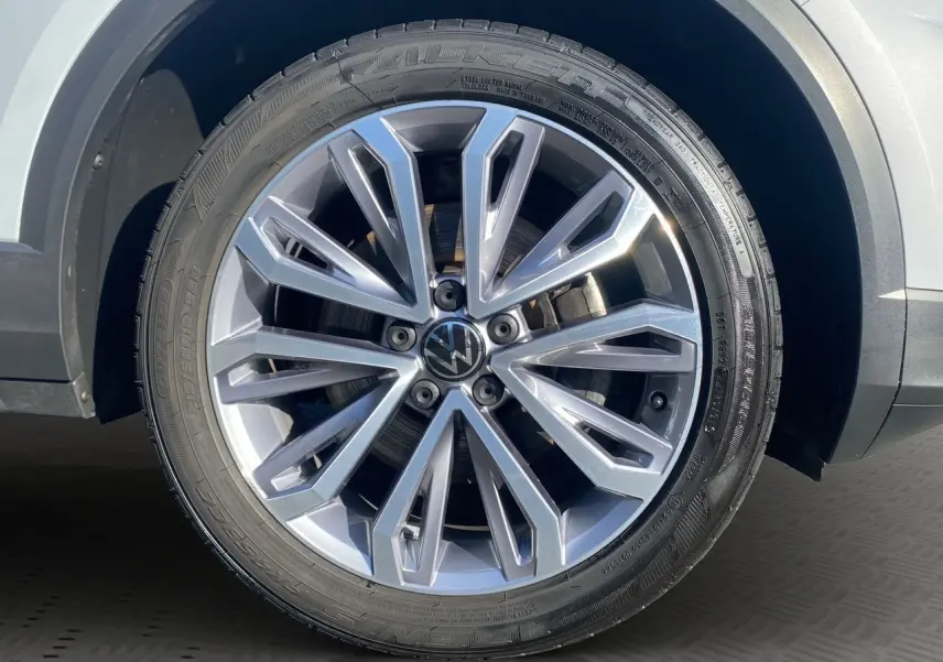 Gros plan sur la jante alu 18 pouces argentée du Volkswagen T-Roc Silver White, mettant en valeur le logo VW central.
