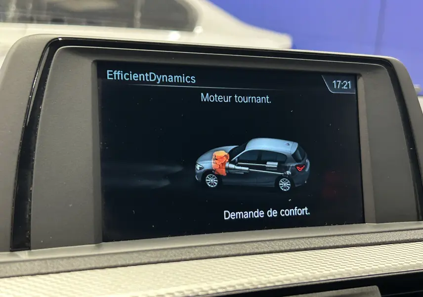 Écran central de BMW Série 1 affichant l'animation moteur tournant avec vue latérale du véhicule gris et toit blanc.