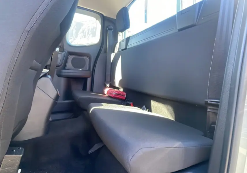 Vue intérieure arrière côté droit du Ford Ranger 2025 gris iconic, montrant la banquette et un kit de secours rouge posé dessus.