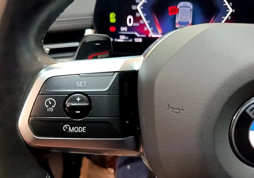 Gros plan sur le côté gauche du volant cuir alu du BMW X1 xDrive23i M Sport 2023 avec commandes de régulateur.