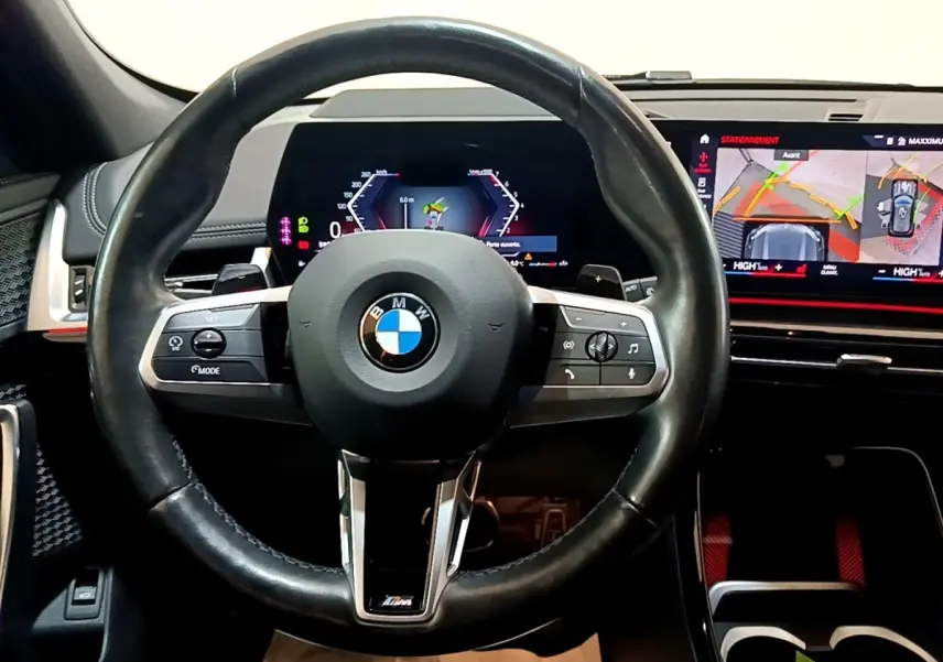 Vue frontale du volant cuir noir BMW X1 xDrive23i M Sport 2023 avec tableau de bord digital et écran tactile de navigation.