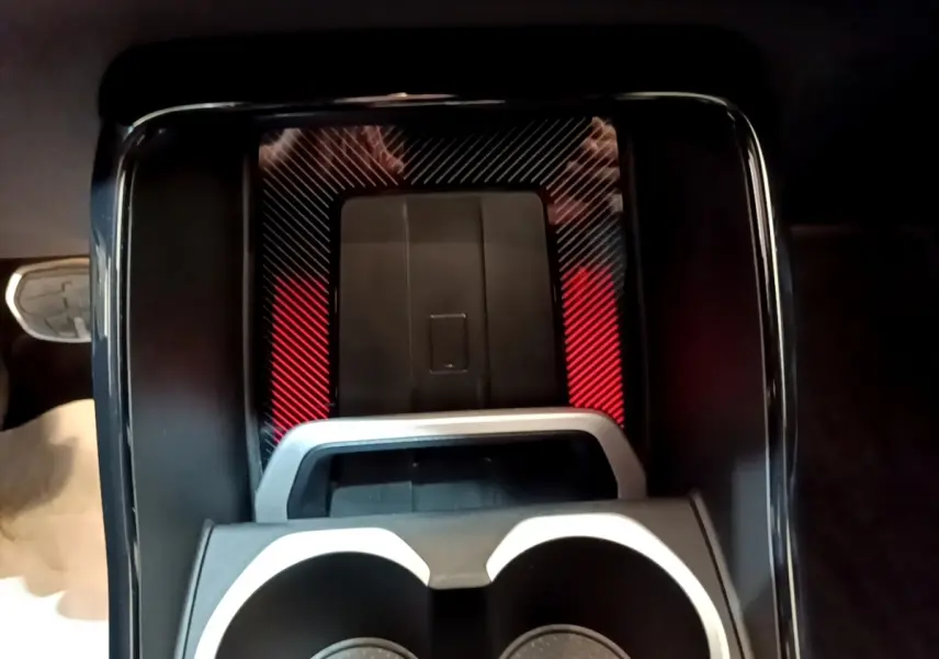 Gros plan sur la console centrale noire avec porte-gobelets et surface à motifs rouges et noirs du BMW X1 xDrive23i M Sport.