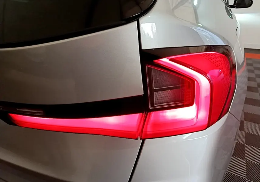 Feu arrière droit allumé sur BMW X1 xDrive23i M Sport gris clair, vue rapprochée du coin arrière du véhicule.
