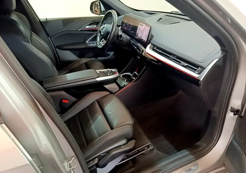 Vue intérieure côté conducteur du BMW X1 xDrive23i M Sport 2023, sièges cuir noirs et tableau de bord numérique.