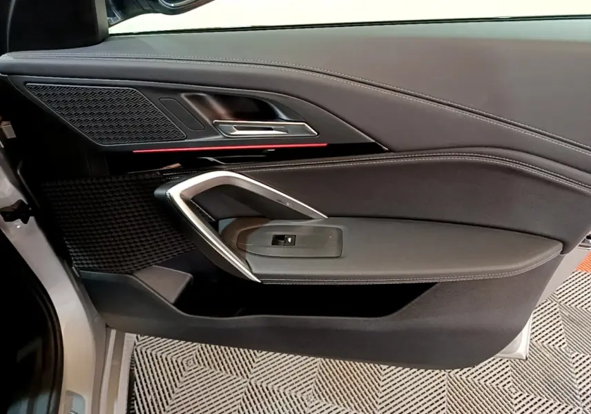 Vue intérieure côté gauche de la porte avant gris clair du BMW X1 xDrive23i M Sport avec garniture noire et insert chromé.