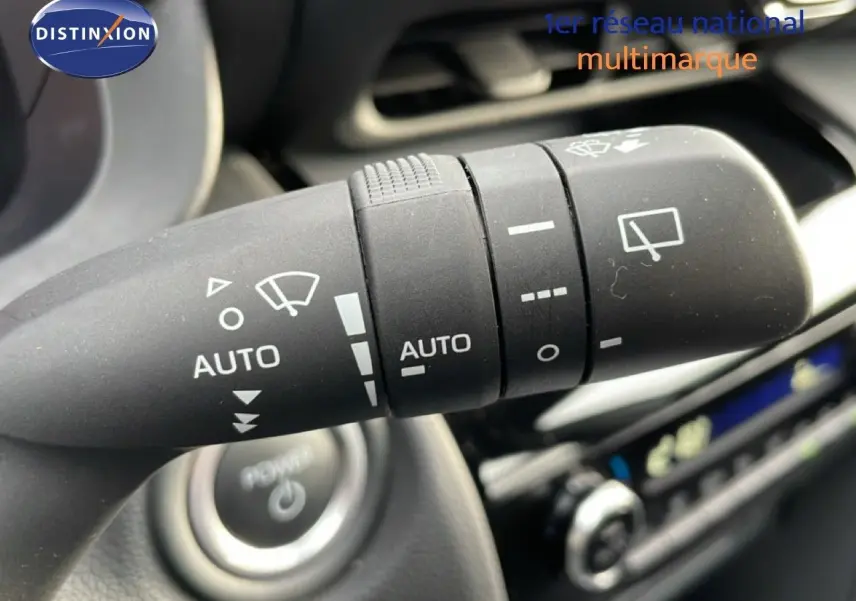 Gros plan sur la manette d’essuie-glace avec commandes automatiques dans l’habitacle d’une Toyota Yaris Cross blanche.