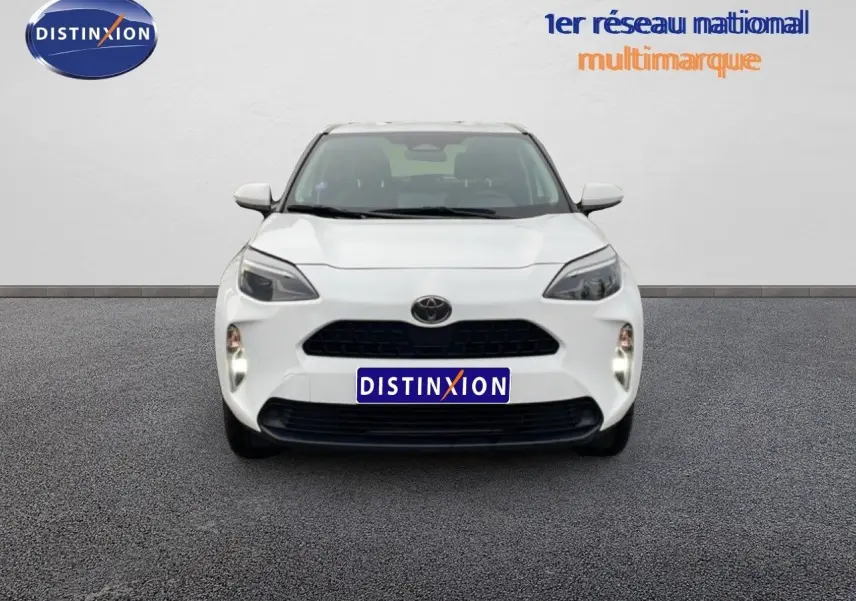 Vue frontale d'une Toyota Yaris Cross 1.5 Hybrid blanche, avec calandre noire et phares LED distinctifs.