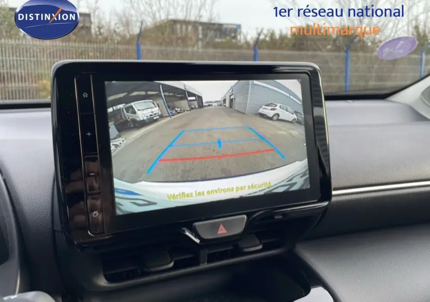 Écran central affichant la caméra de recul d'une Toyota Yaris Cross blanche, vue intérieure du tableau de bord.