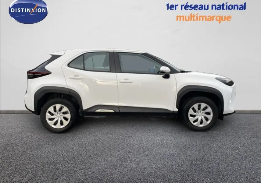 Profil côté droit de la Toyota Yaris Cross 2024 blanche, soulignant ses lignes modernes et ses protections noires contrastantes.