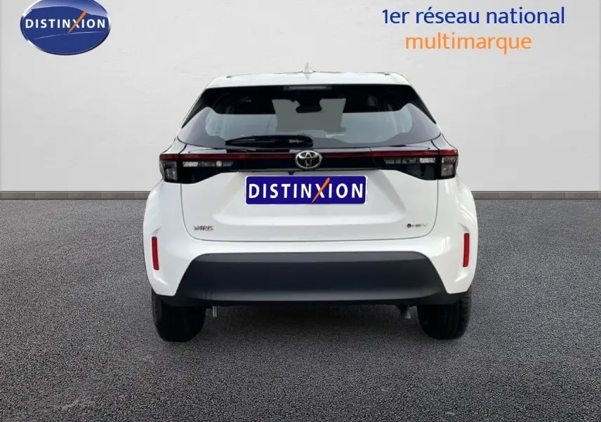 Vue arrière de la Toyota Yaris Cross 2024 blanche, soulignant son bandeau lumineux noir et son pare-chocs contrasté.