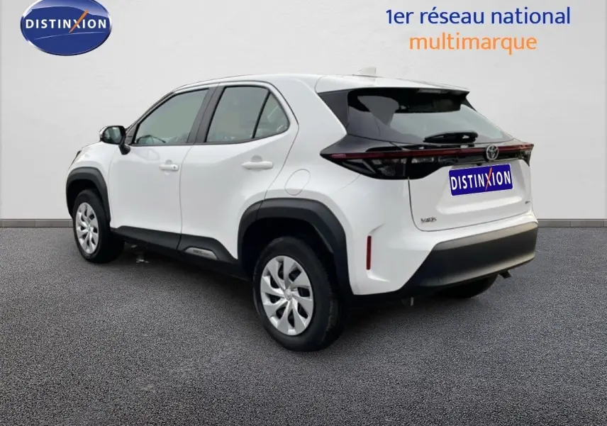 Toyota Yaris Cross blanc pur en 3/4 arrière droit, avec protections noires et feux arrière étirés.