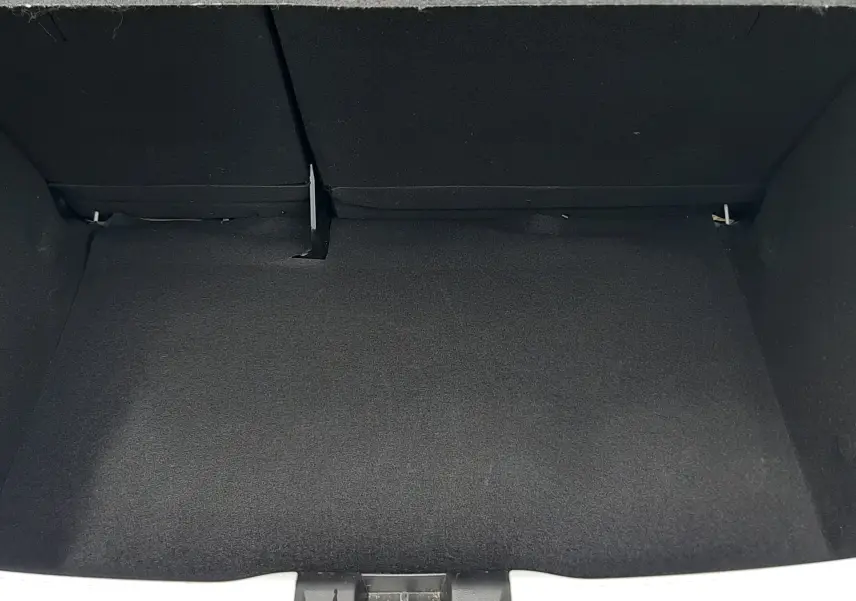 Coffre ouvert vu de face d'une Dacia Sandero blanc glacier 2024, espace de chargement vide et tapis noir.