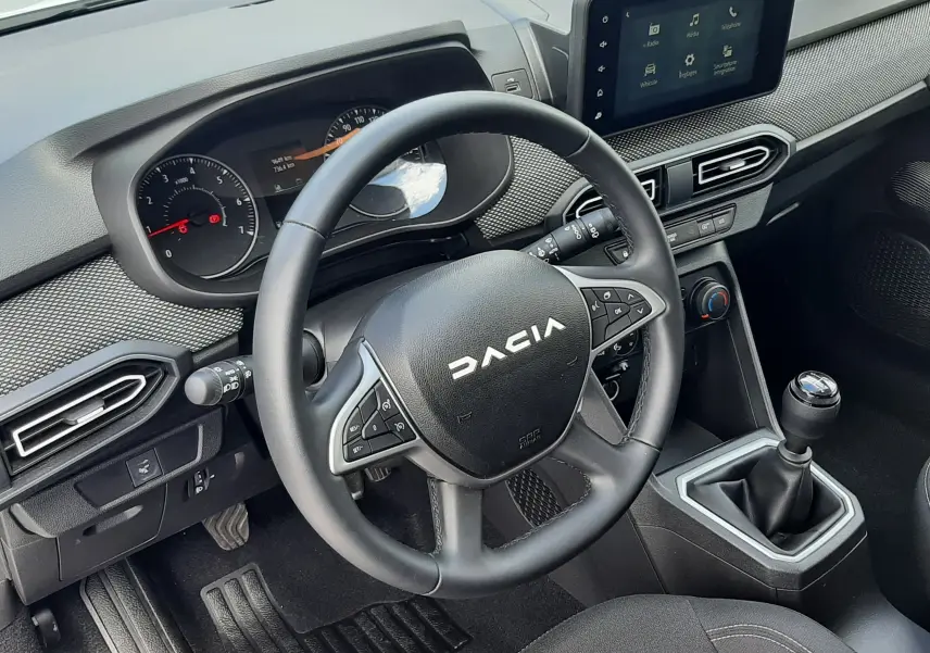 Vue intérieure côté conducteur du tableau de bord et volant DACIA Sandero 2024, finition noire avec boîte manuelle.