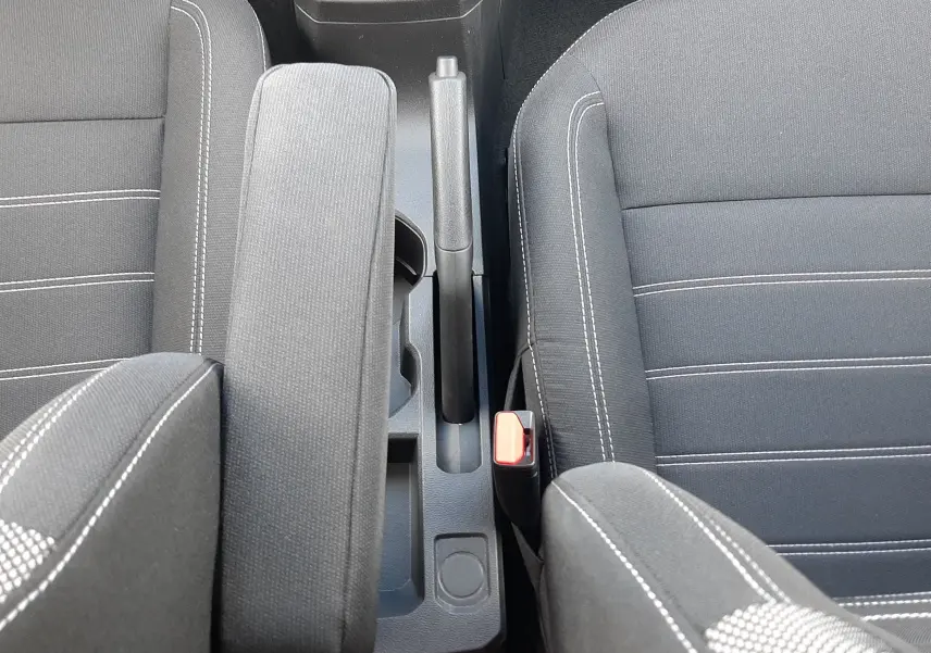 Vue plongeante sur l'intérieur noir tissu de la Dacia Sandero 2024, avec levier de frein à main et accoudoir central.