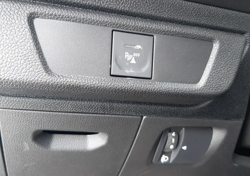 Gros plan sur le tableau de bord noir de la Dacia Sandero 2024, montrant le bouton de désactivation du radar de recul.