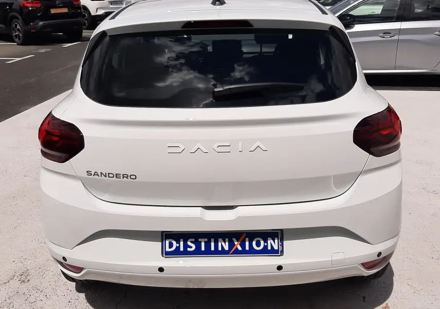 Vue arrière d'une Dacia Sandero blanc glacier 2024 avec feux arrière rouges et plaque d'immatriculation Distinxion.