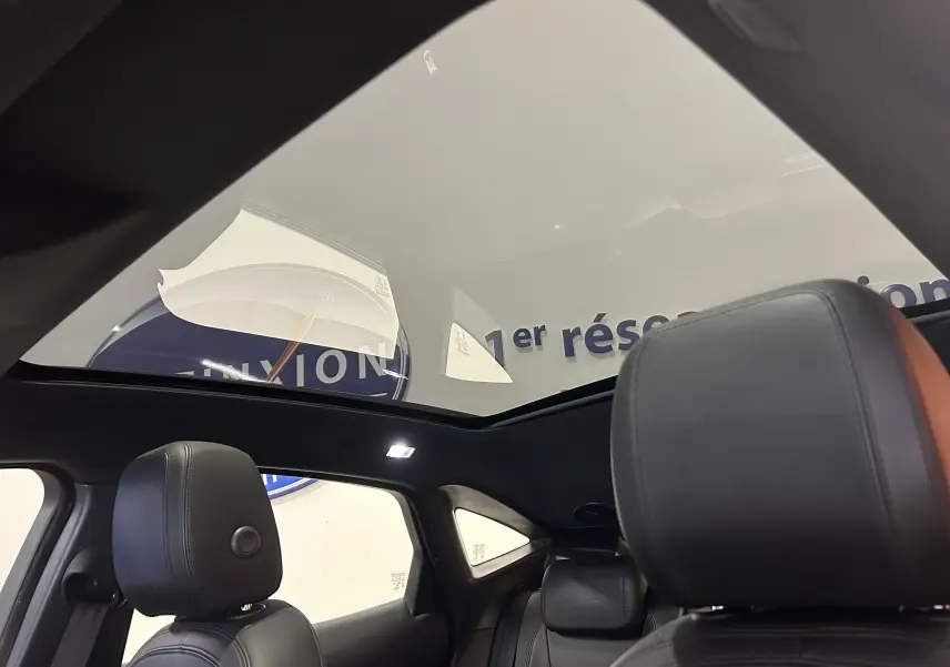 Vue intérieure du toit panoramique du Jaguar E-PACE beige 2018, avec sièges en cuir noir et éclairage LED.