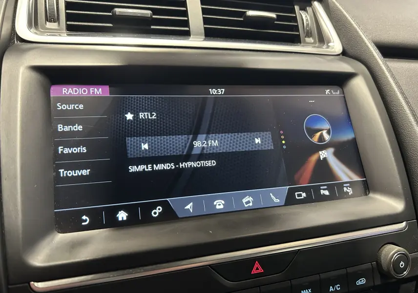 Écran tactile central de la Jaguar E-PACE beige affichant la radio FM sur RTL2 à 98,2 MHz, intérieur noir.