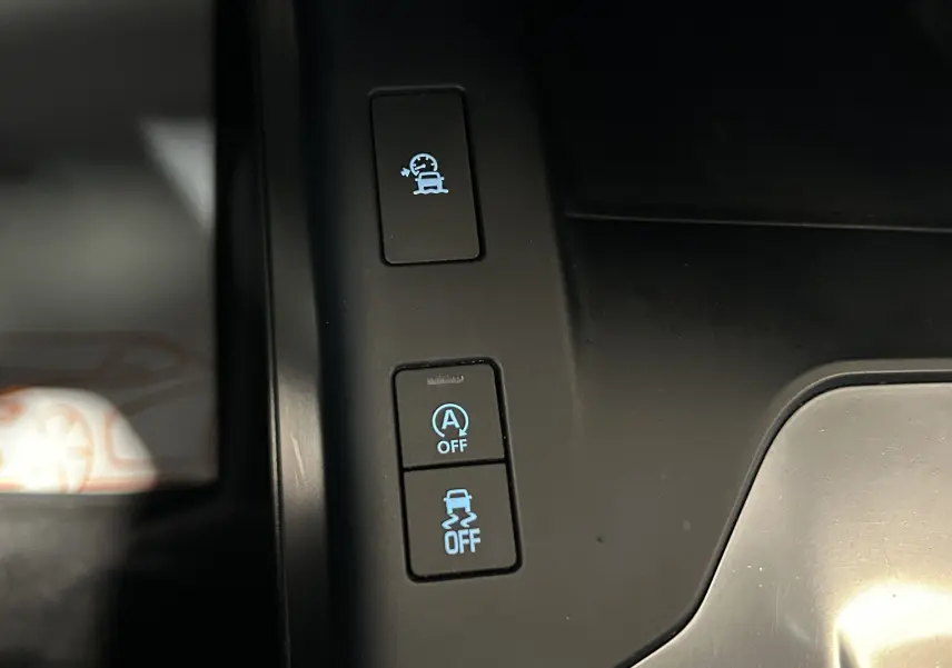Gros plan sur les boutons de contrôle d’assistance à la conduite dans l’habitacle noir d’une Jaguar E-PACE beige.