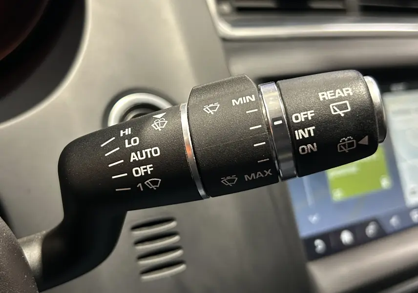 Gros plan sur la commande des essuie-glaces dans l’habitacle du Jaguar E-PACE beige, avec affichage des réglages visibles.