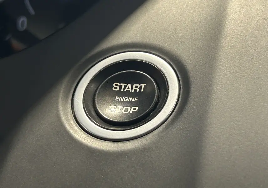 Bouton start/stop moteur en gros plan sur le tableau de bord du Jaguar E-PACE beige, version 2018.
