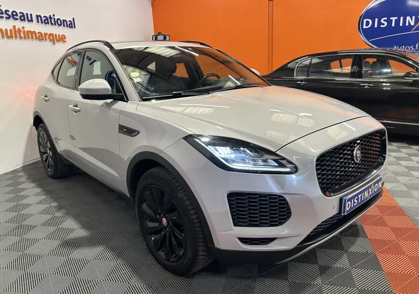 Jaguar E-PACE beige vue 3/4 avant droit avec calandre noire et jantes noires en showroom.
