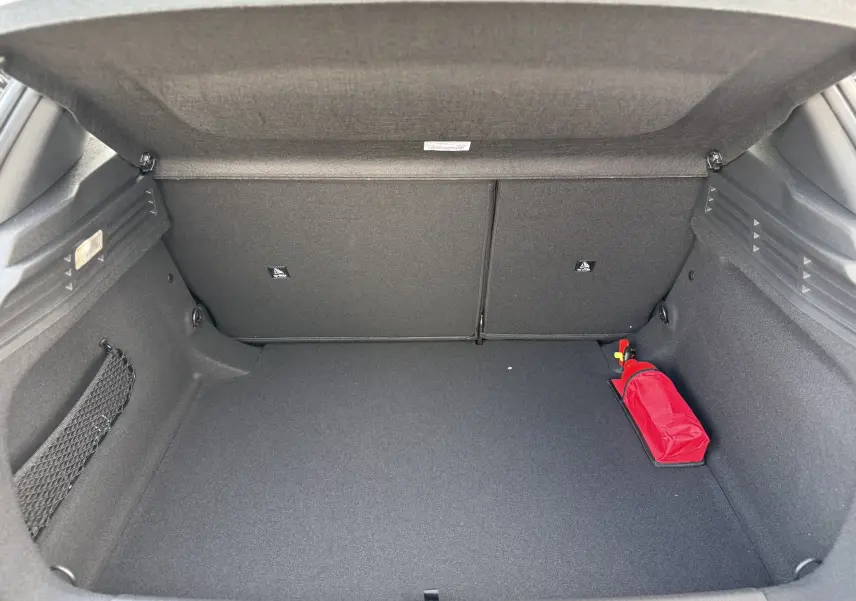 Coffre ouvert d'une Peugeot 308 gris Artense, montrant un espace vide avec un triangle de signalisation rouge à droite.