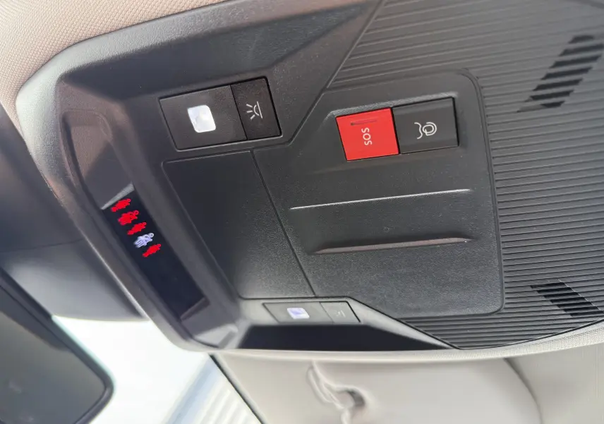 Vue en gros plan du panneau de commandes au plafond intérieur de la Peugeot 308 gris Artense, avec bouton SOS rouge et éclairage.