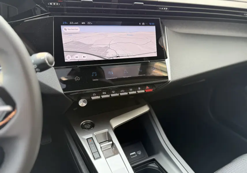 Vue intérieure centrée sur la console centrale et l'écran tactile de la Peugeot 308 2025 gris Artense, avec navigation affichée.