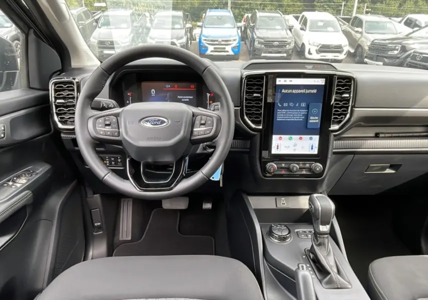 Vue intérieure du Ford Ranger 2025 gris carbone, tableau de bord moderne avec écran tactile vertical et volant multifonction.