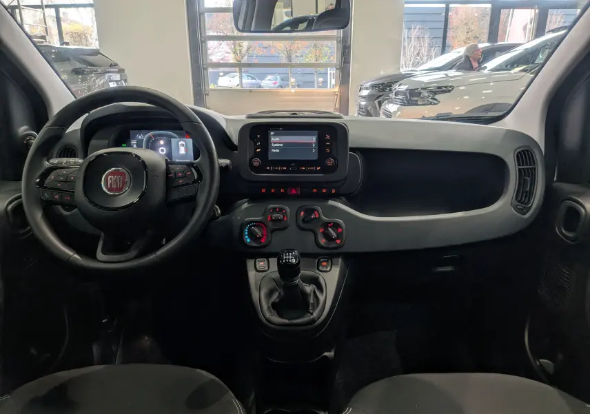 Vue intérieure du tableau de bord de la Fiat Panda 1.0 Hybrid 2025 avec volant multifonction et écran tactile central.