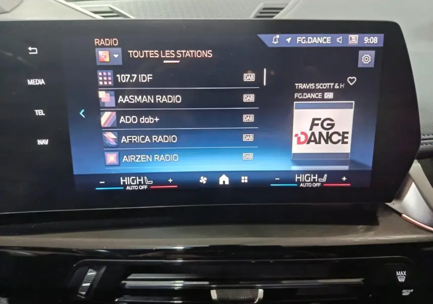 Écran tactile central affichant les stations radio dans l’habitacle du BMW X1 blanc, vue de face.