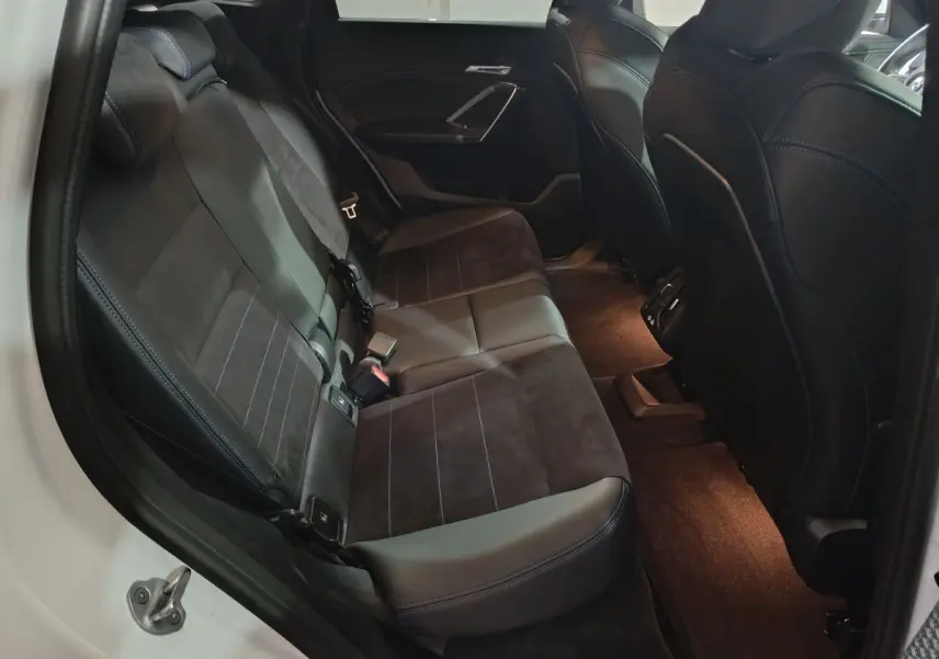 Vue intérieure côté gauche des sièges arrière en cuir noir et alcantara du BMW X1 xDrive25e blanc 2024.