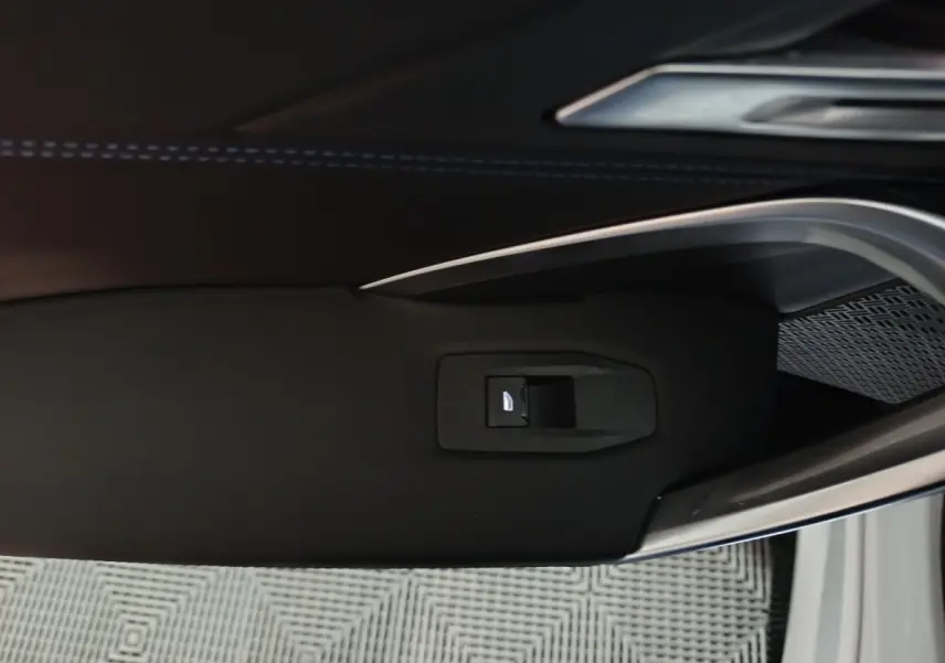 Gros plan sur la poignée intérieure noire de la porte côté gauche d’un BMW X1 blanc 2024.