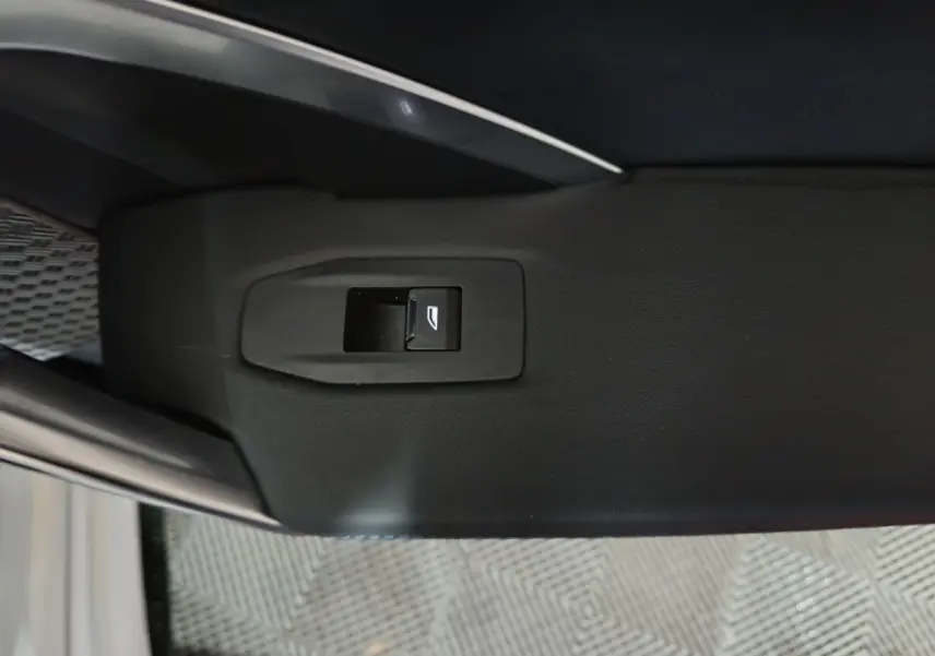 Bouton de commande de lève-vitre sur la portière intérieure côté gauche d’un BMW X1 blanc 2024.