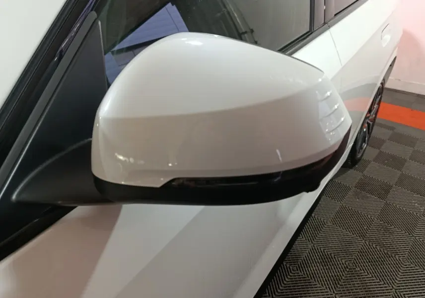 Gros plan sur le rétroviseur droit blanc du BMW X1 xDrive25e M Sport 2024, avec clignotant intégré noir.