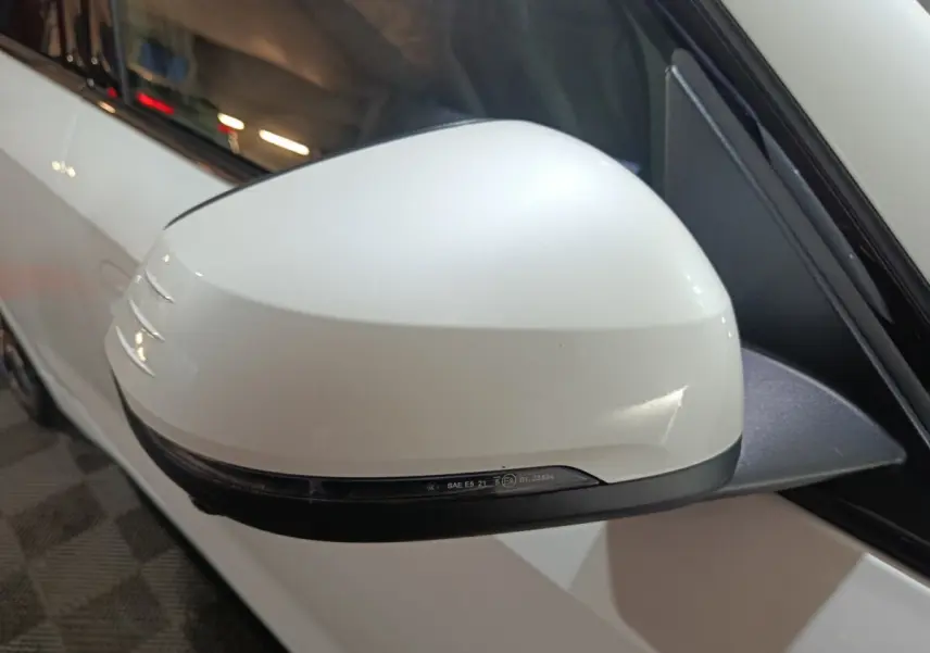 Rétroviseur blanc côté gauche d'une BMW X1 xDrive25e 2024, avec clignotant intégré et carrosserie blanche visible.
