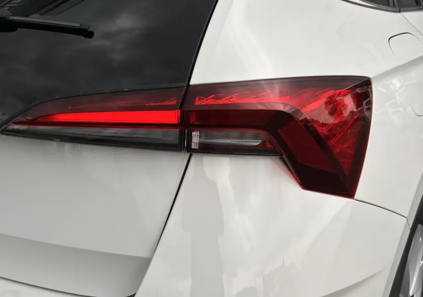 Gros plan sur le feu arrière droit rouge vif d’une Skoda Scala blanche Candy, avec lunette arrière surteintée visible.